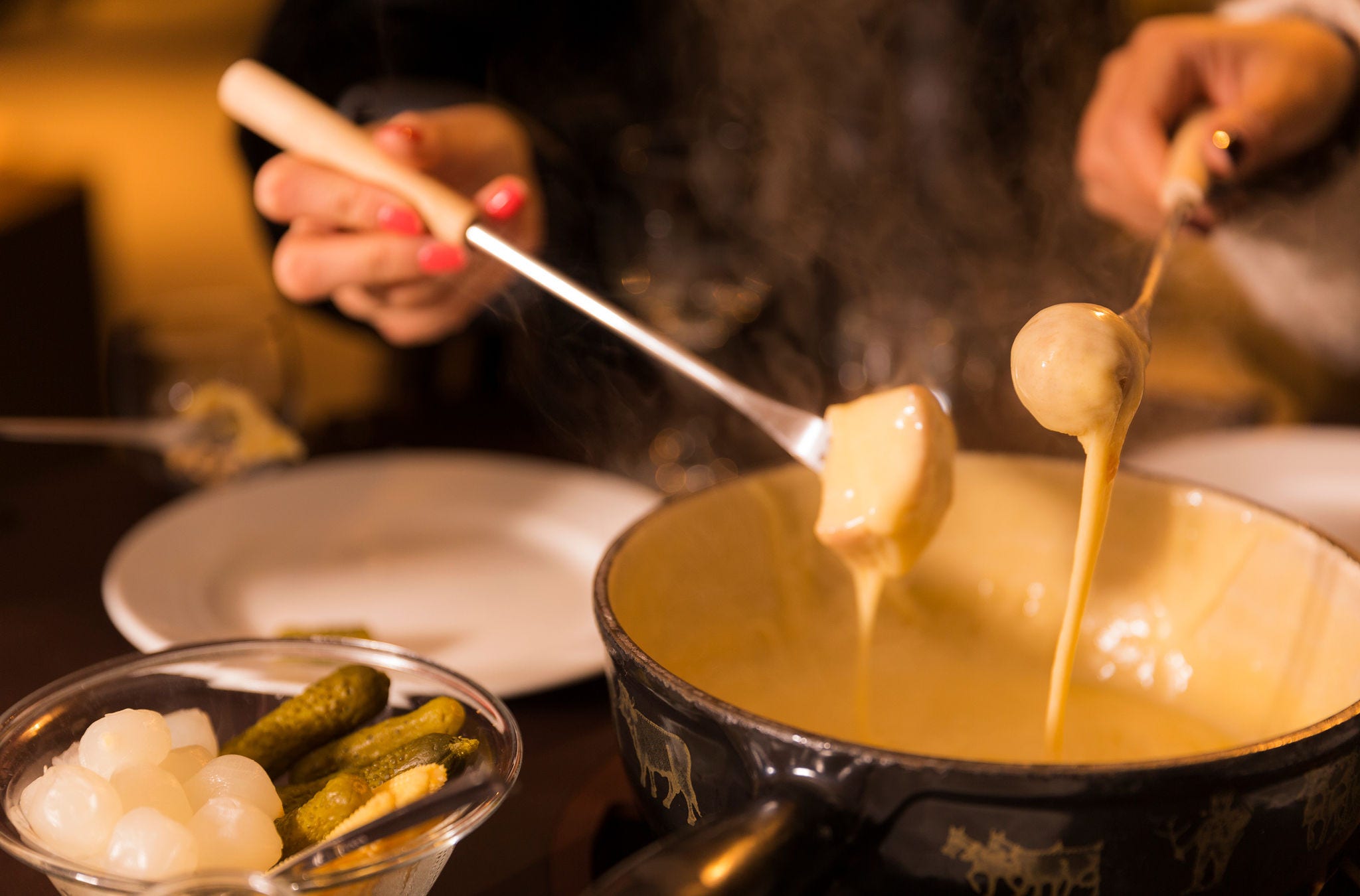 Zwei Personen tauchen Brot ins Fondue. 