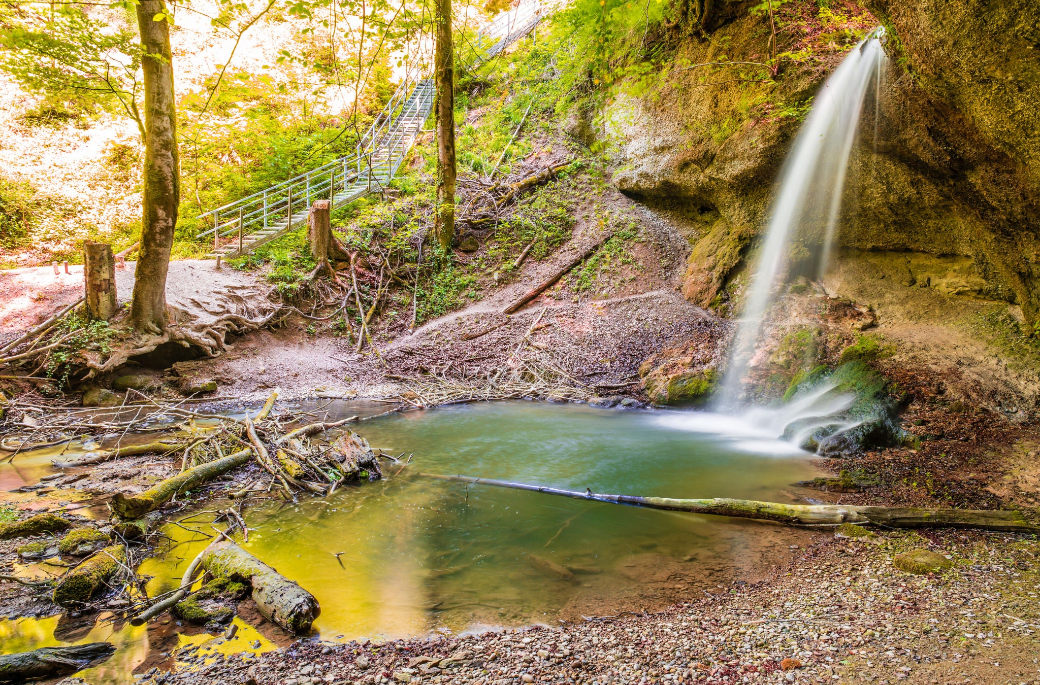 Ein Wasserfall mit kleinem Teich mitten im Wald.