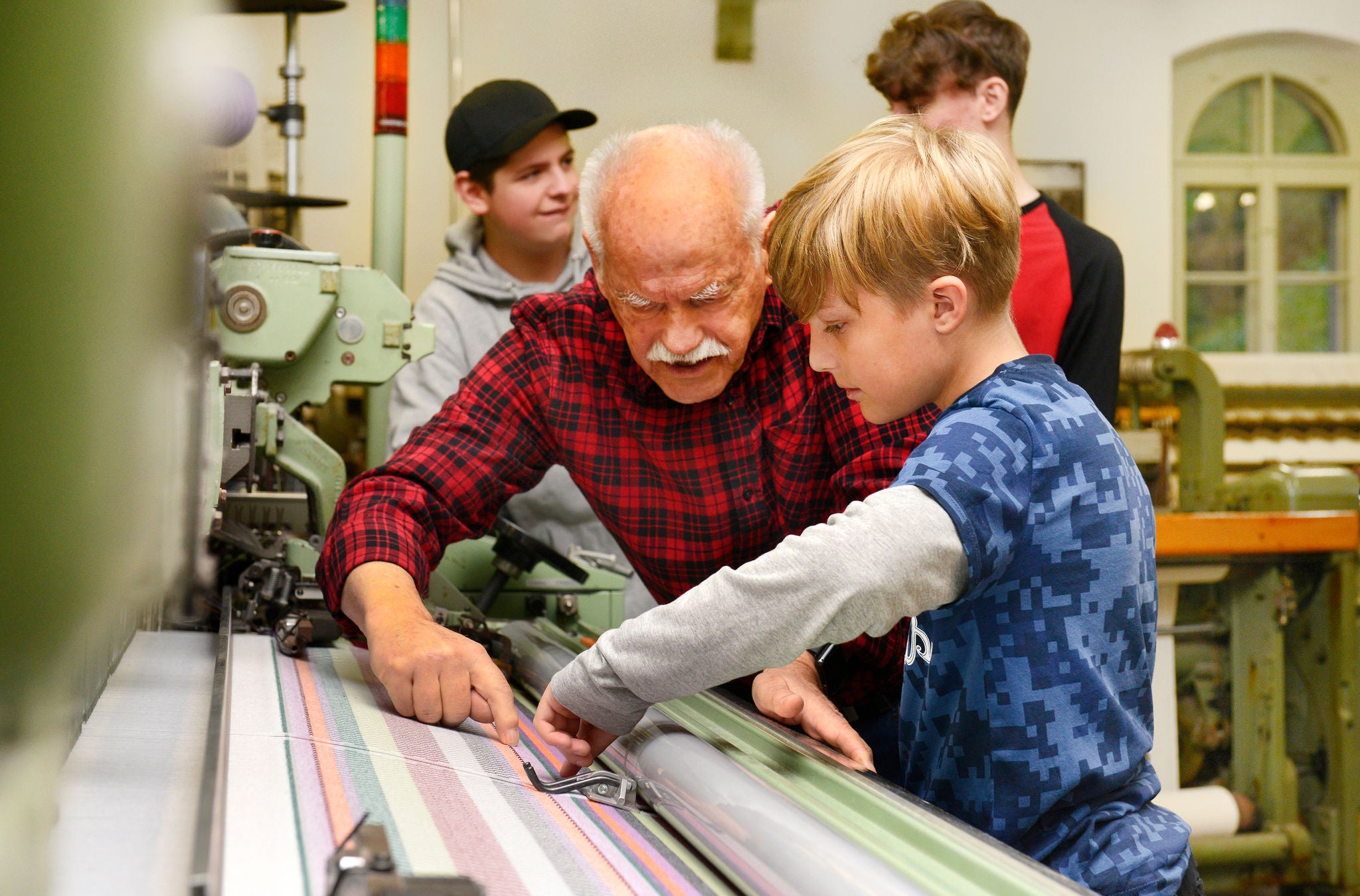 Museumsmitarbeter zeigt Kind eine Maschine