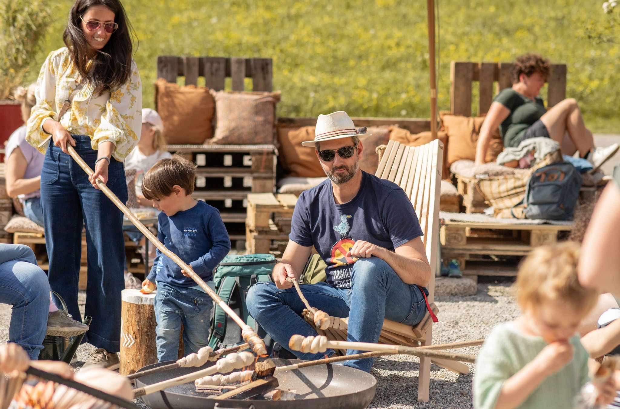 Familie sitzt um Grillstelle.
