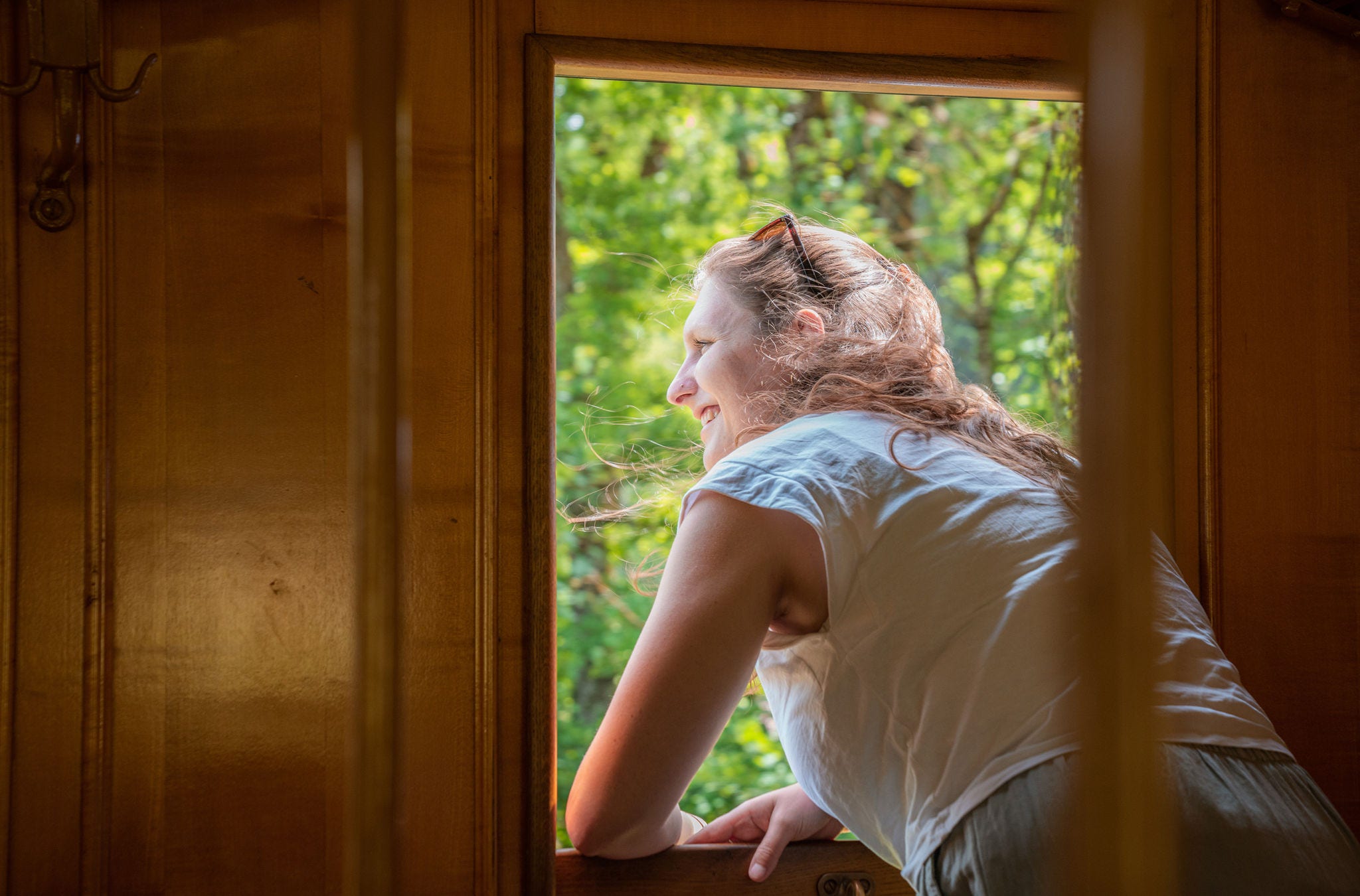 Eine Frau schaut während der Fahrt mit der Dampfbahn aus dem Fenster.