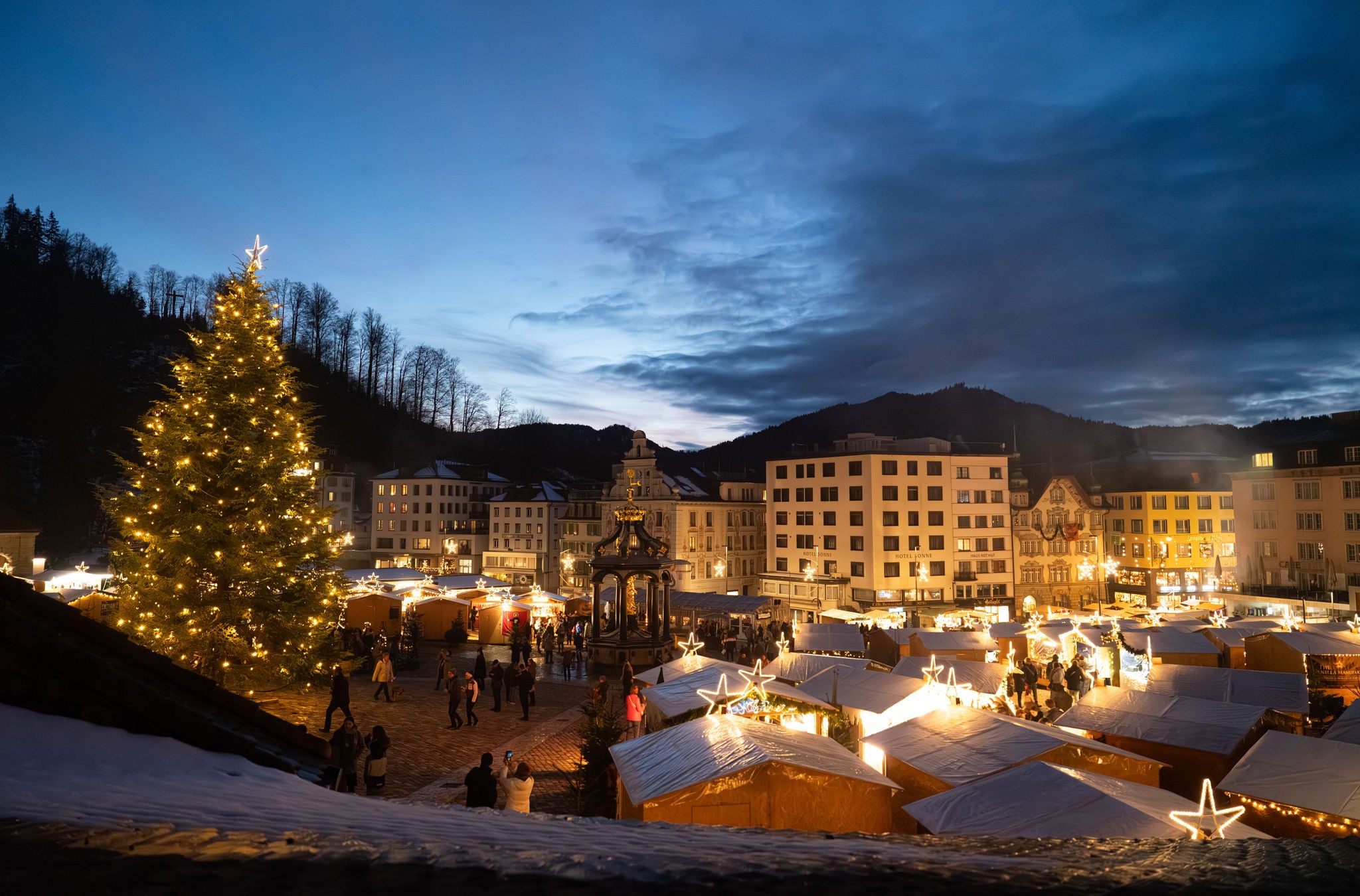 Die Verkaufsstände des Einsiedler Weihnachtsmarkt mit Weihnachtsbaum am Abend. 