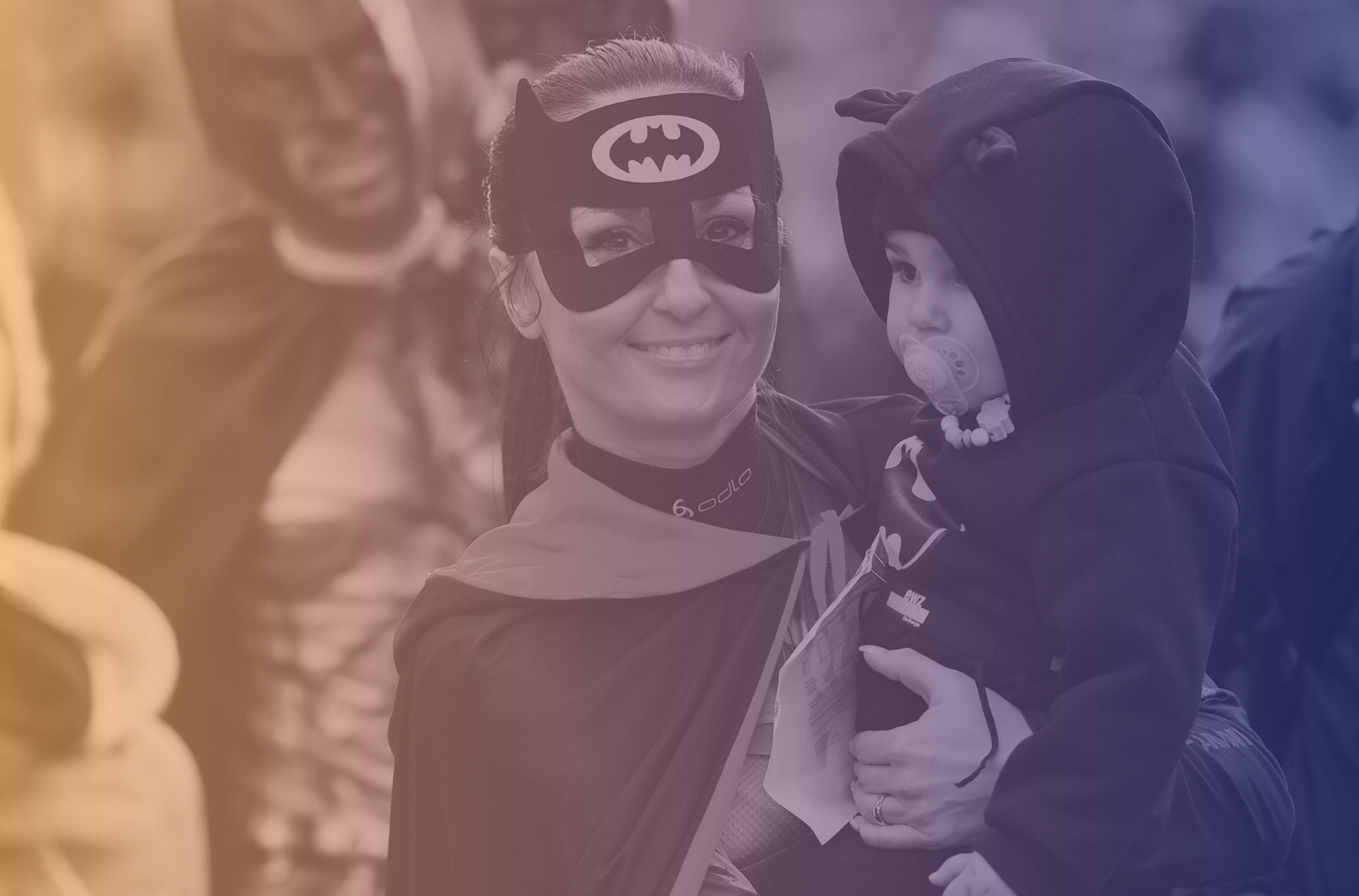 Eine als Batman verkleidete Frau nimmt am Zürcher Silvesterlauf teil und trägt ihr Kind auf dem Arm.