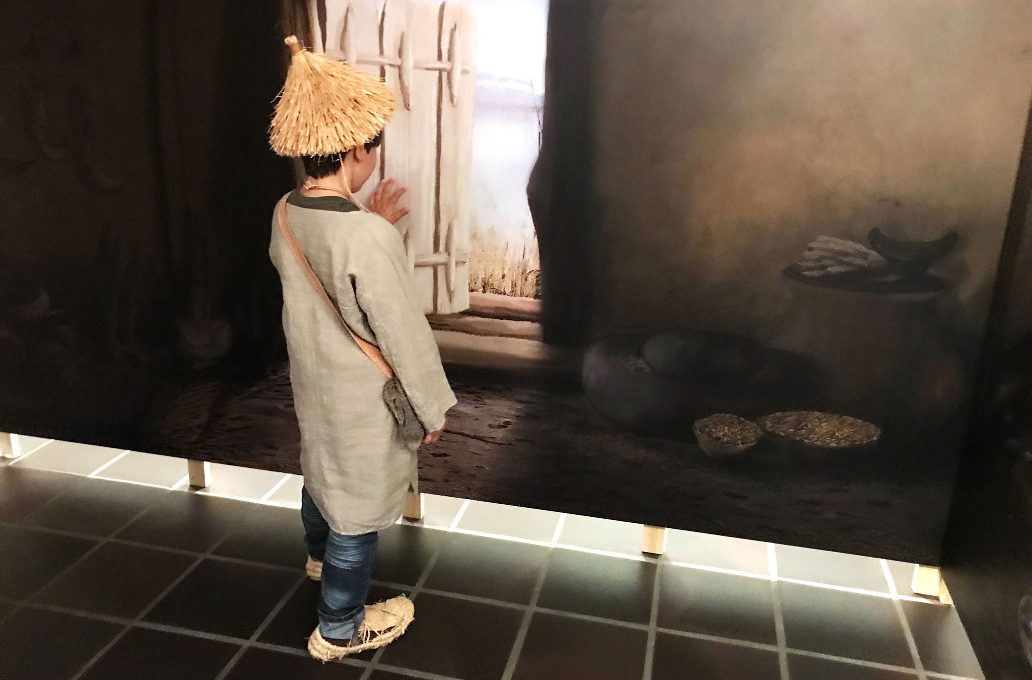 Ein Kind mit Strohhut steht vor einem Fenster im Museum Wetzikon. 