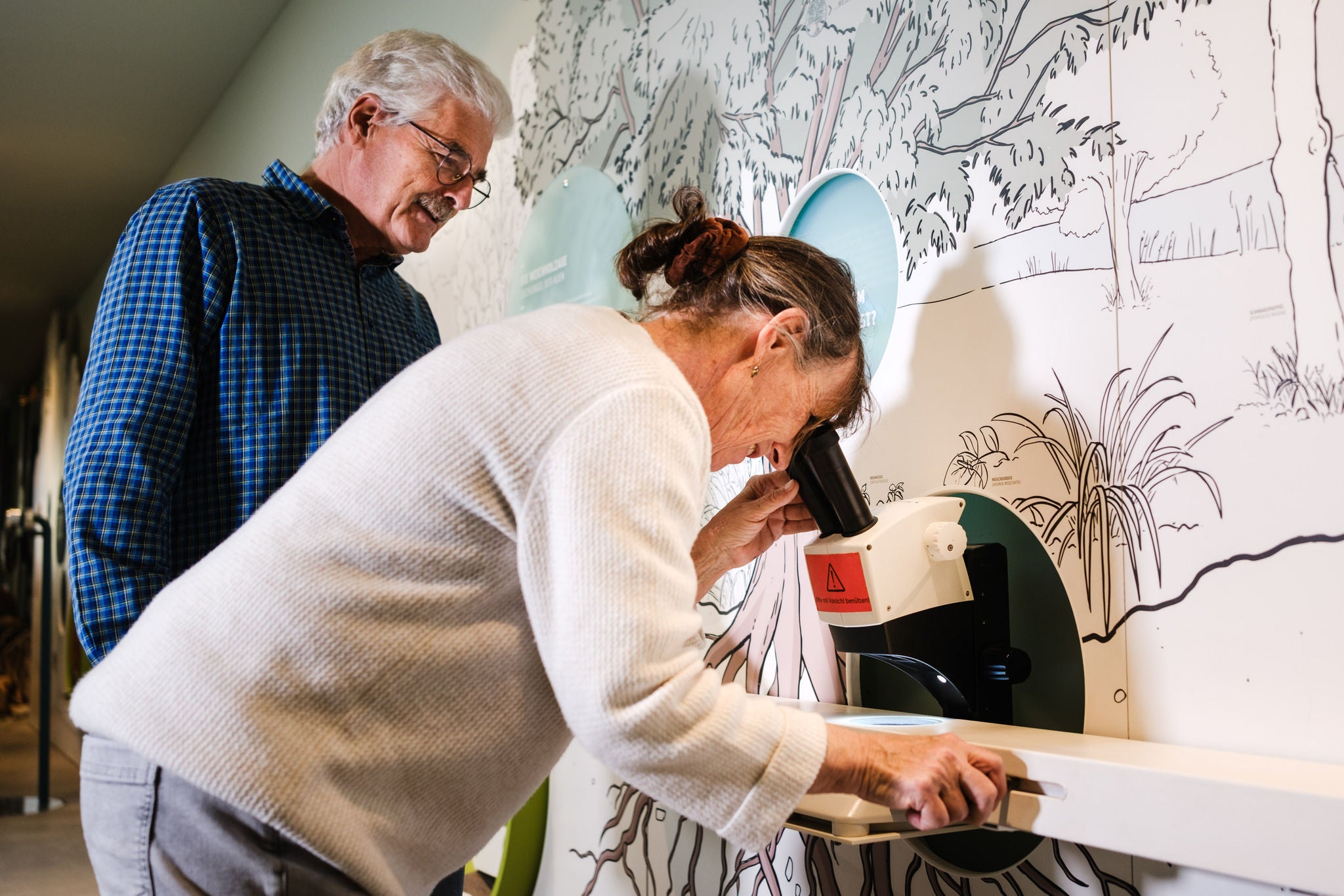 Zwei Personen in der Ausstellung im Naturzentrum Thurauen am Mikroskop.