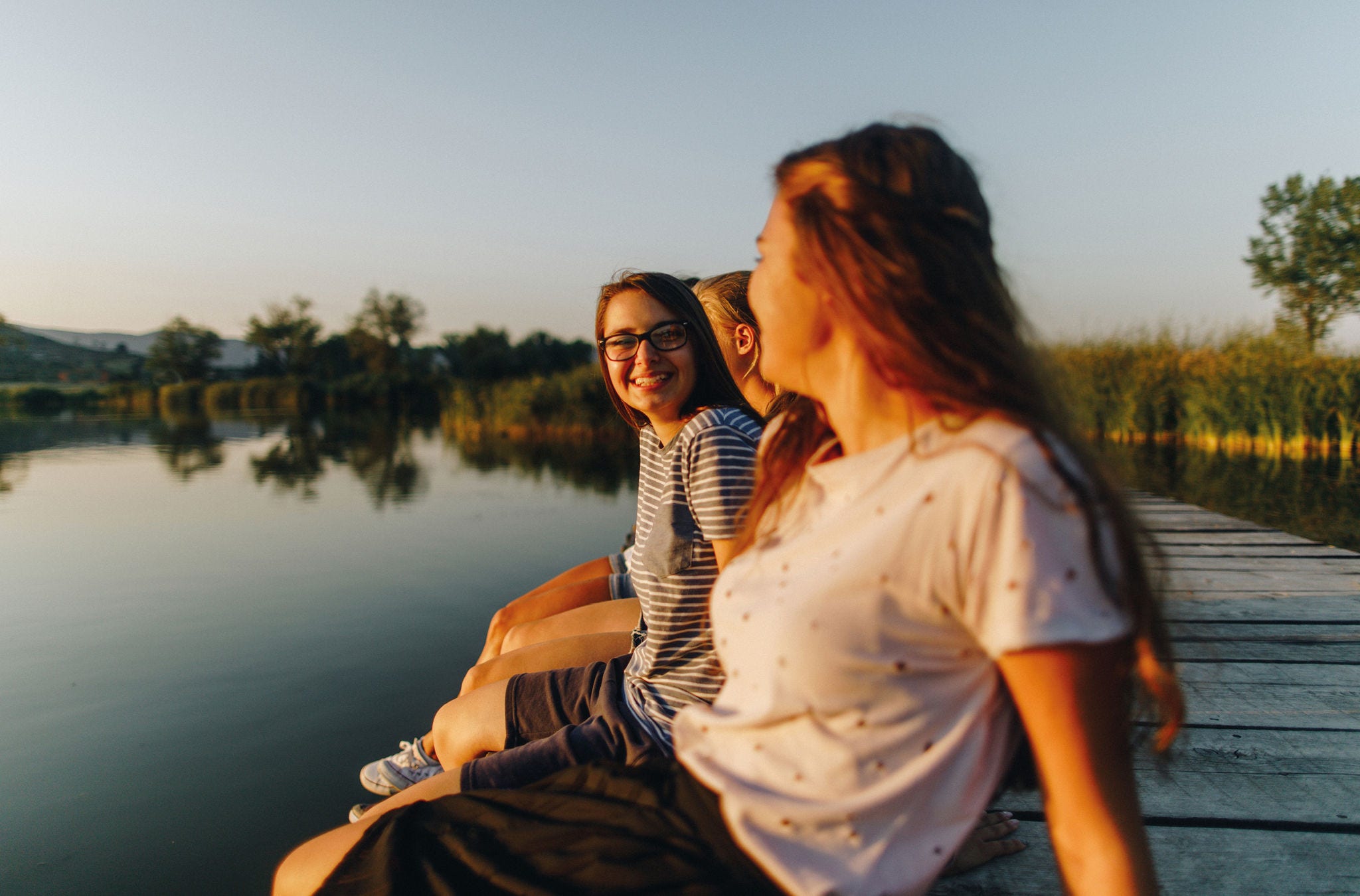 Eine Freundesgruppe sitzt an einem Teich. 