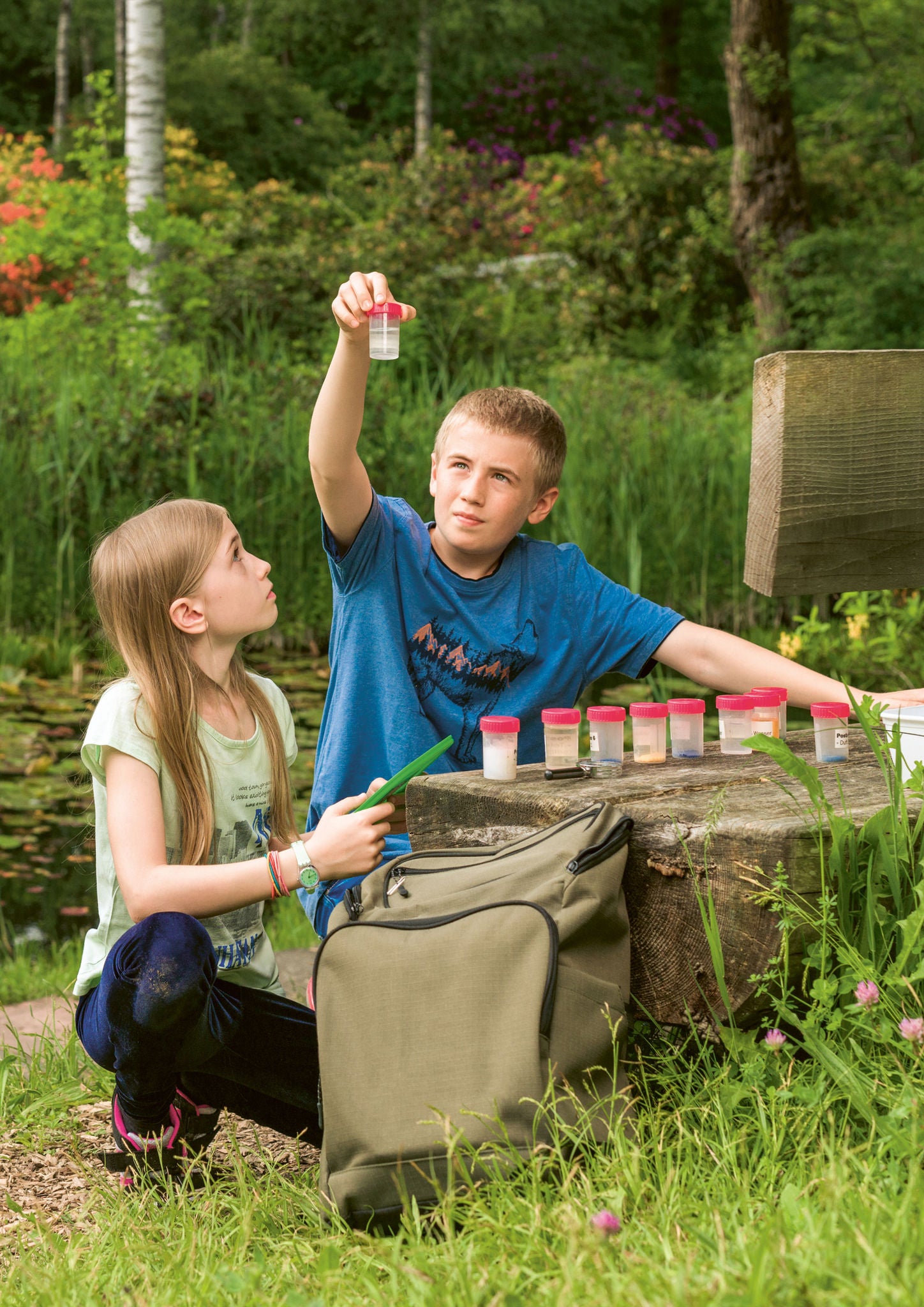 Zwei Kinder im Seleger Moor untersuchen verschiedene Becher mit Proben.