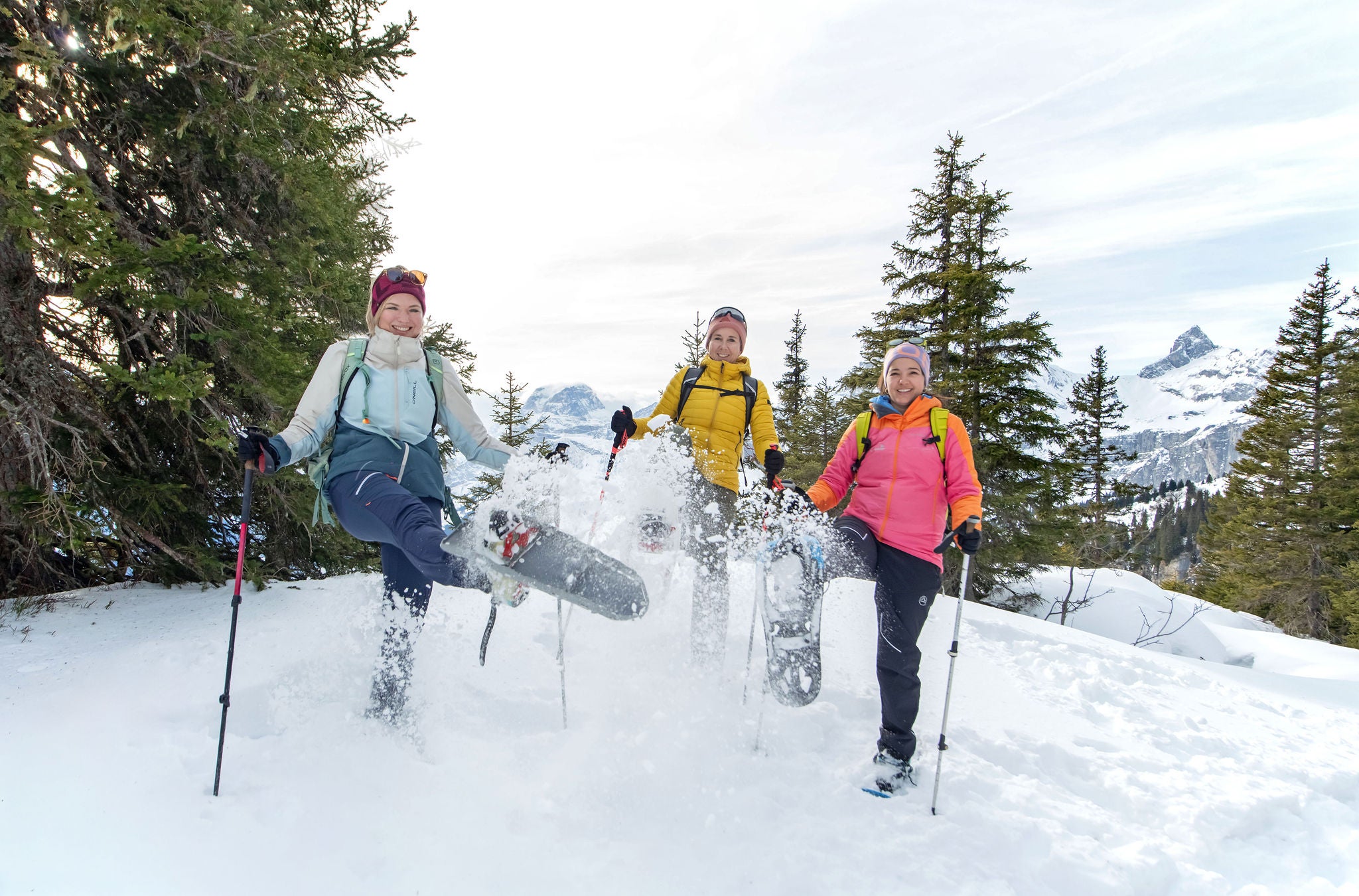 Drei Frauen halten je einen Schneeschuh in die Höhe. 