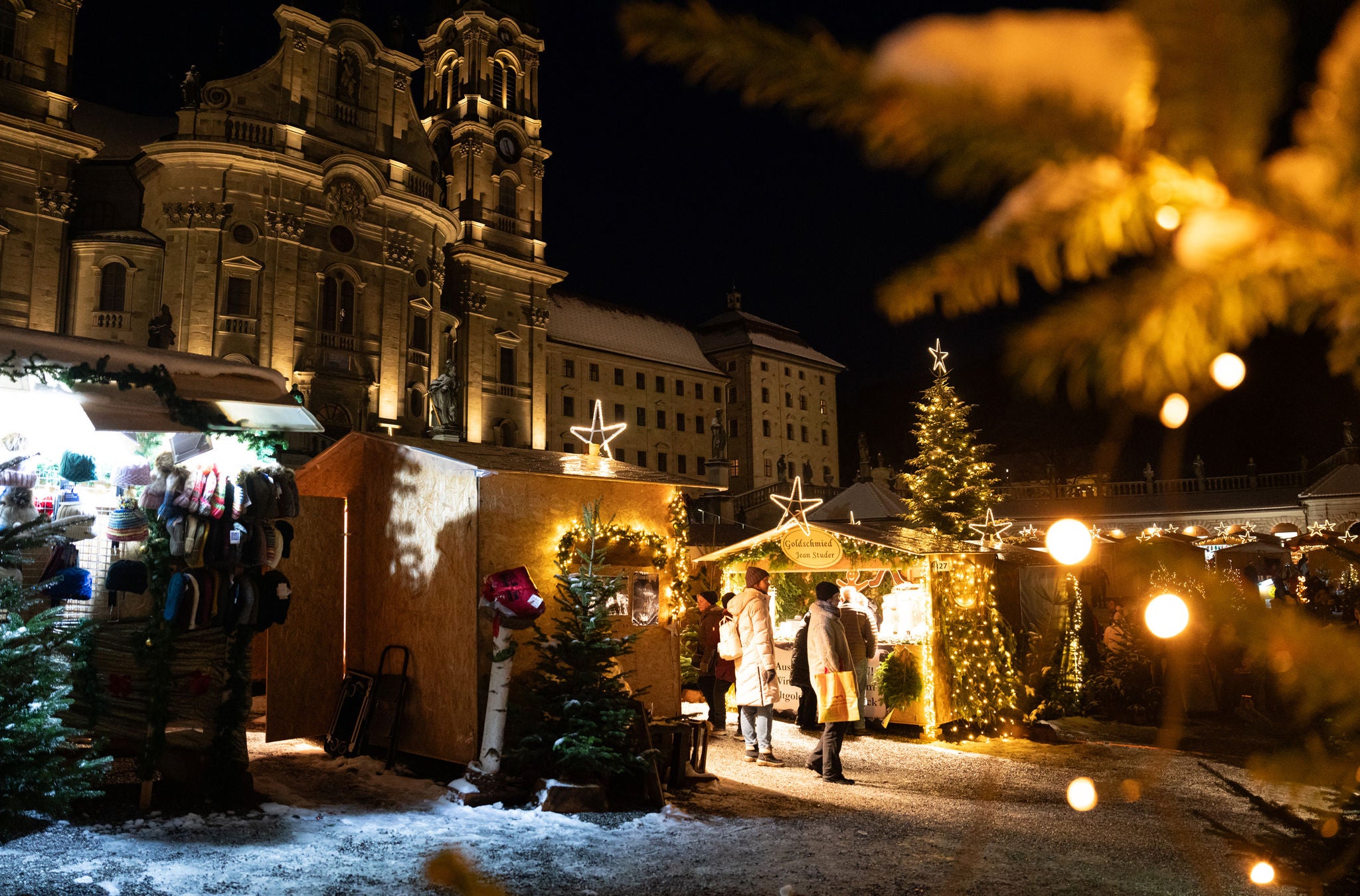 Verkaufsstände des Einsiedler Weihnachtsmarkt am Abend mit hellen Lichtern. 