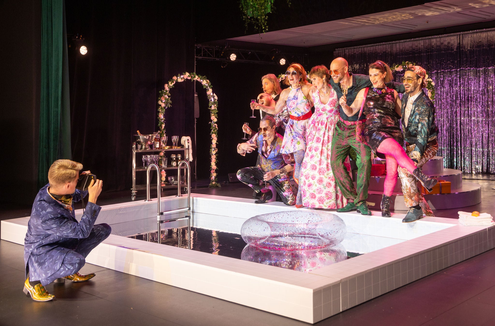 Ein Fotograf macht ein Foto von Darsteller und Darstellerinnen auf der Bühne. 