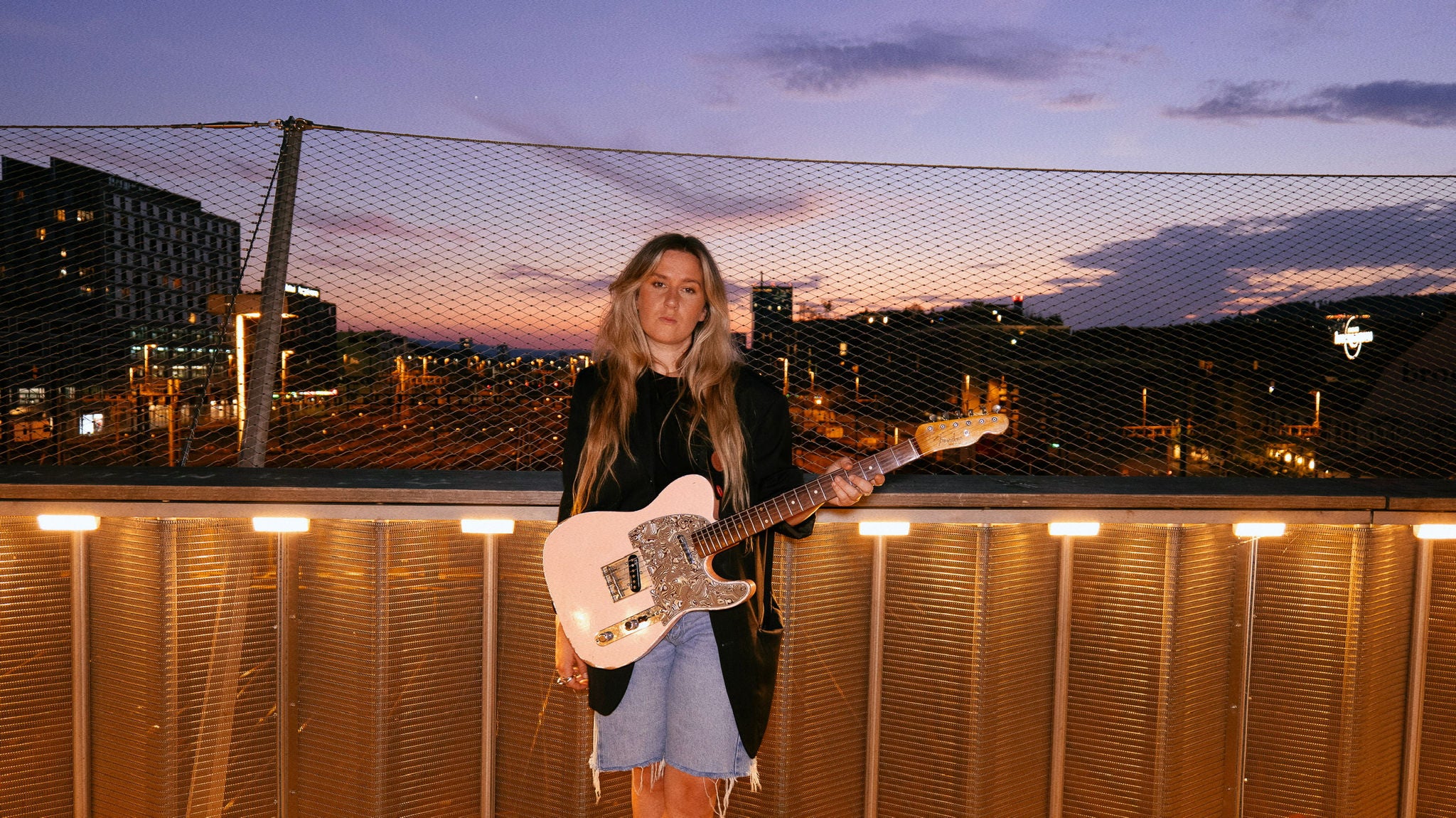 Frau mit Gitarre in der Hand auf einer Brücke. 