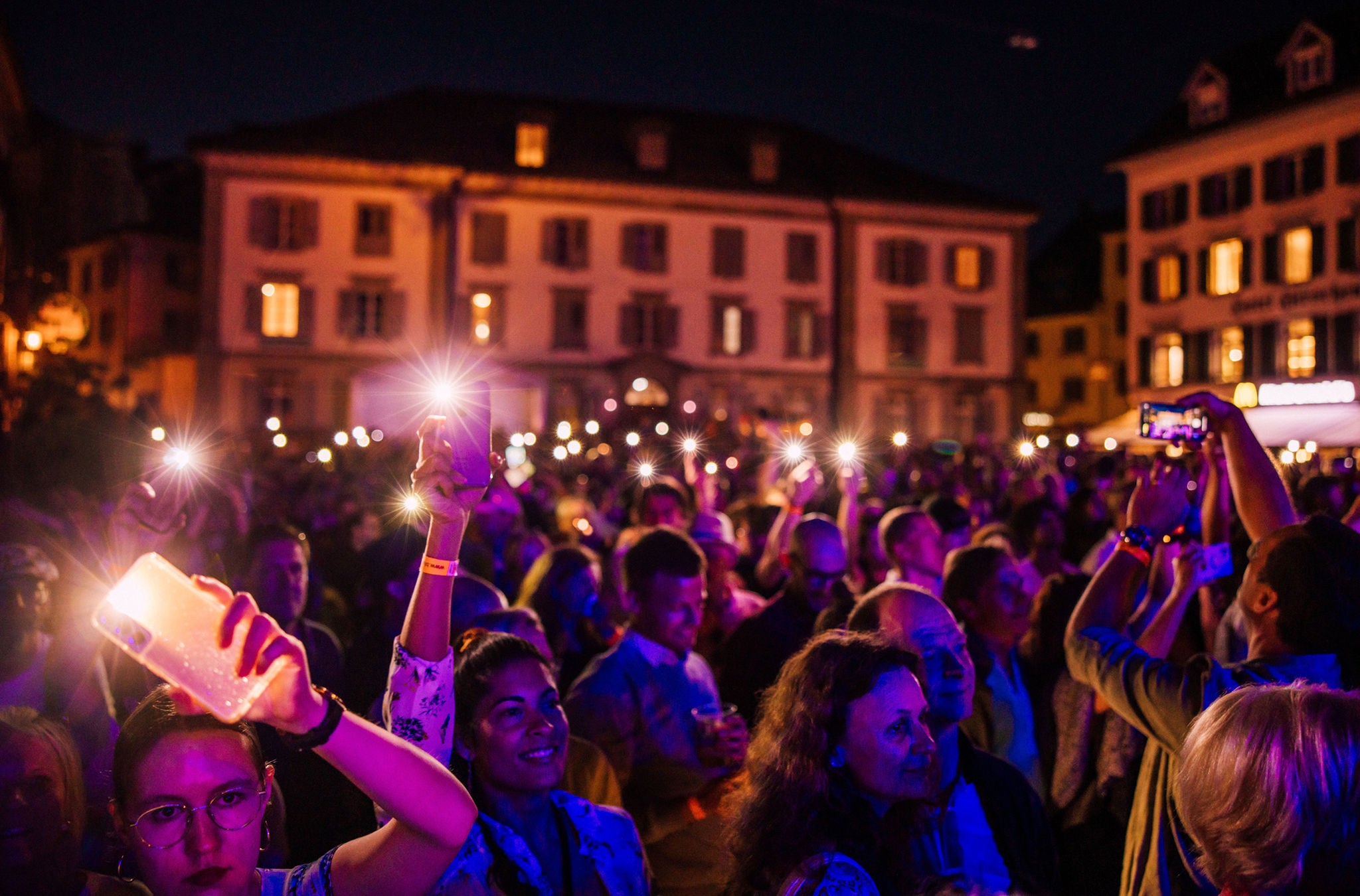 Menschen stehen vor einer Bühne mit Lichter. 