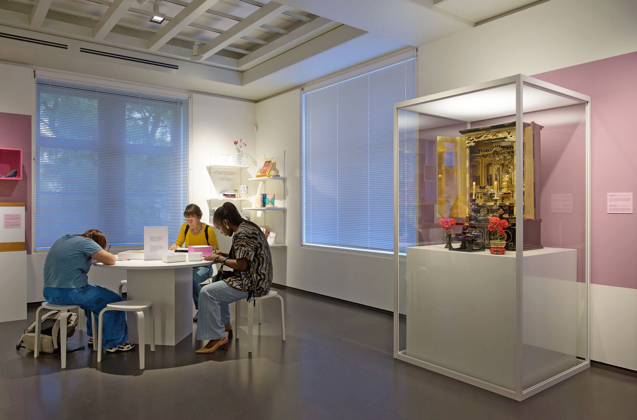 Drei Personen sitzen um einen Tisch im Völkerkundemuseum der Universität Zürich.