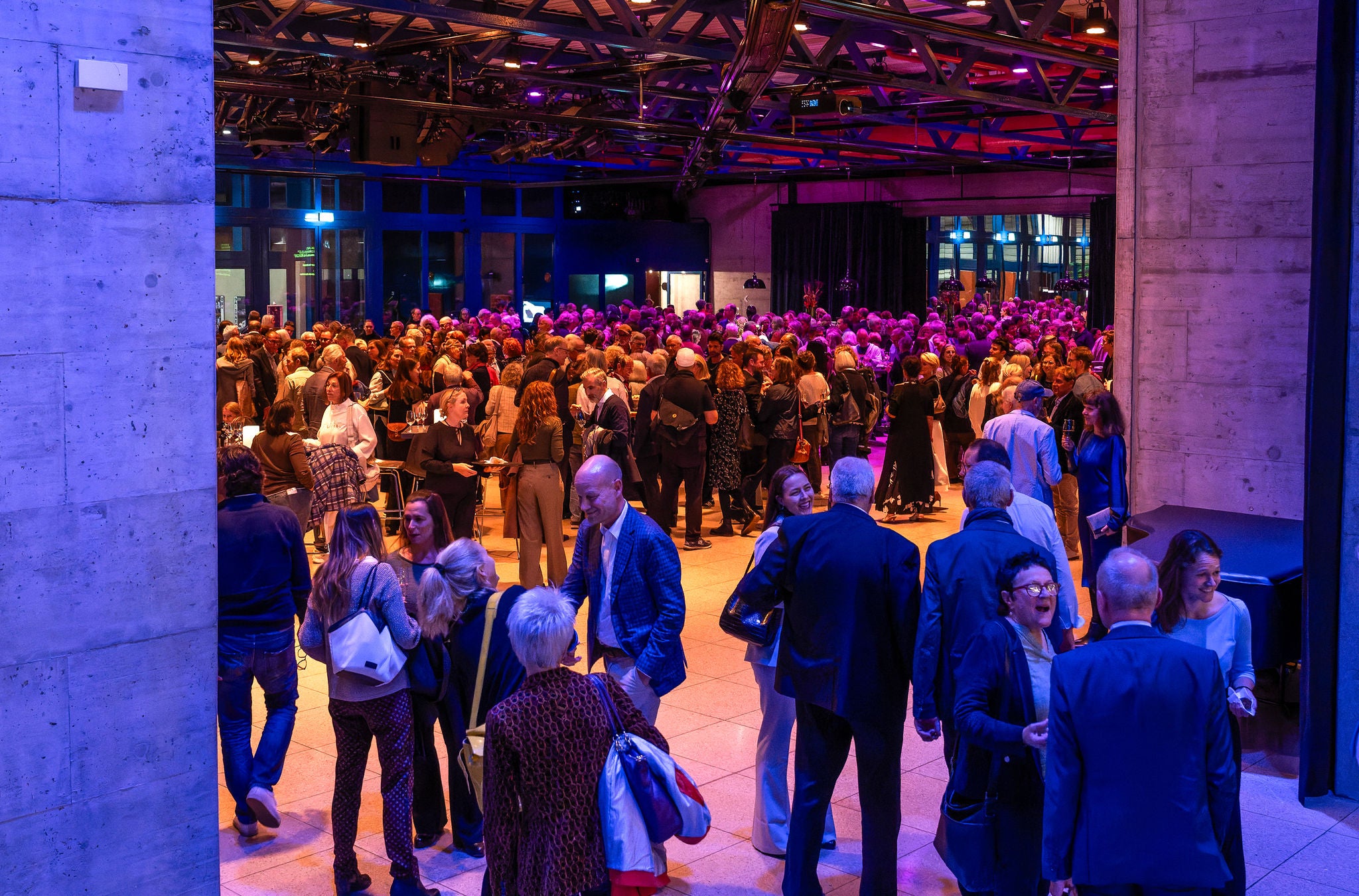 Viele Besuchende stehen in einer grossen Halle. 
