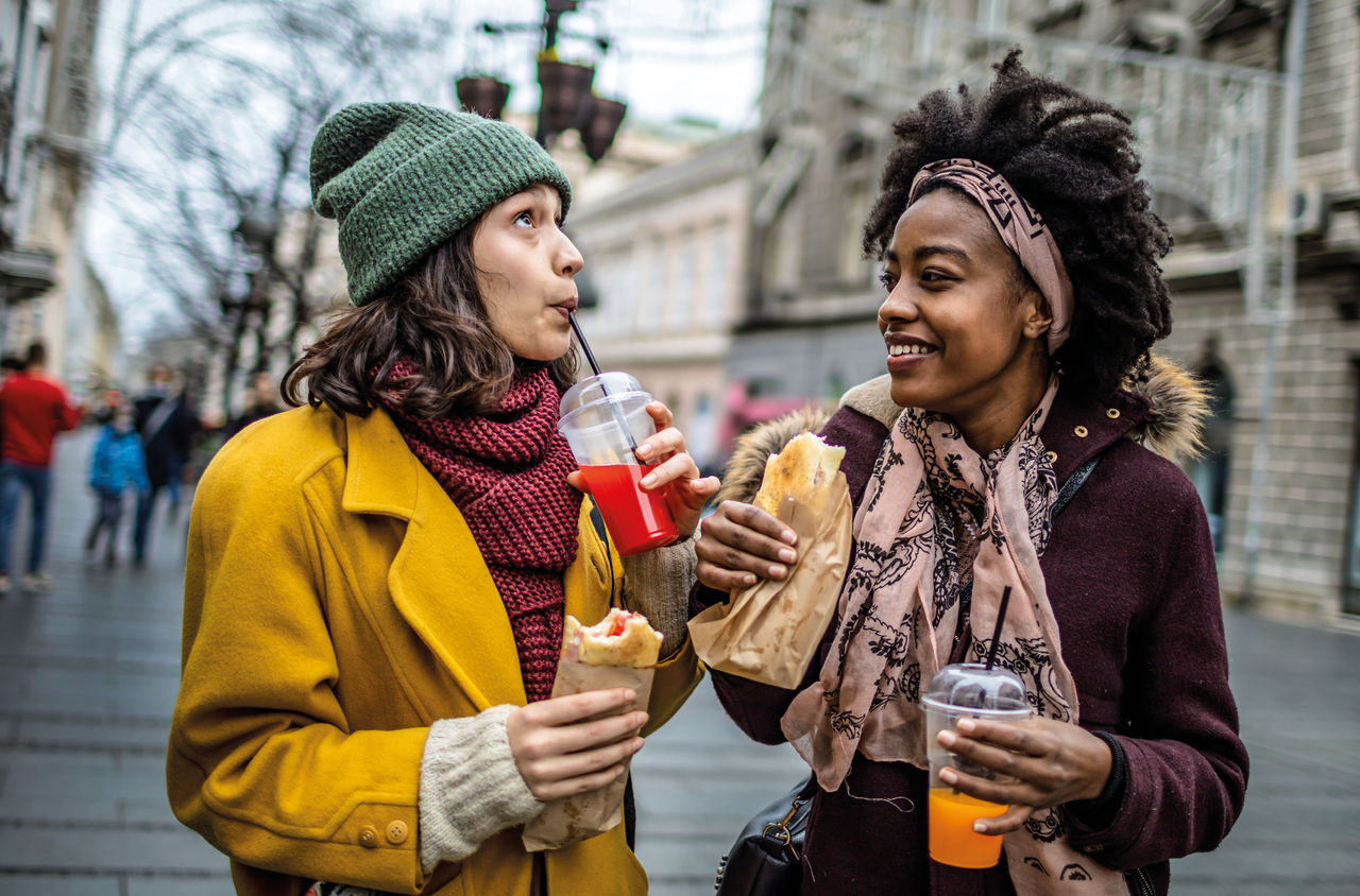 Zwei Frauen mit Getränken und Verpflegung in der Stadt im Winter. 