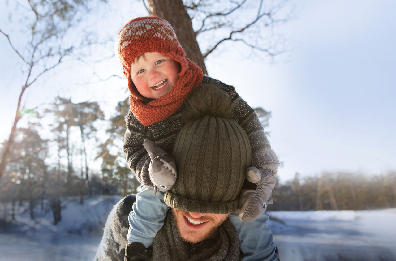 Ein Kind sitzt auf den Schultern eines Erwachsenen. 