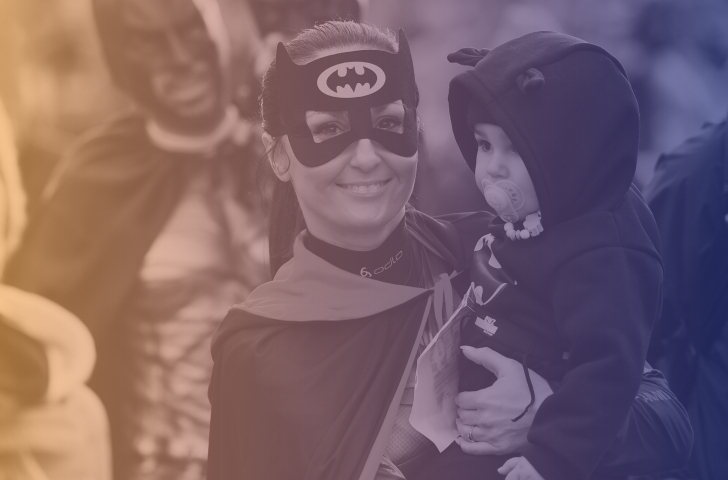 Eine als Batman verkleidete Frau nimmt am Zürcher Silvesterlauf teil und trägt ihr Kind auf dem Arm. 