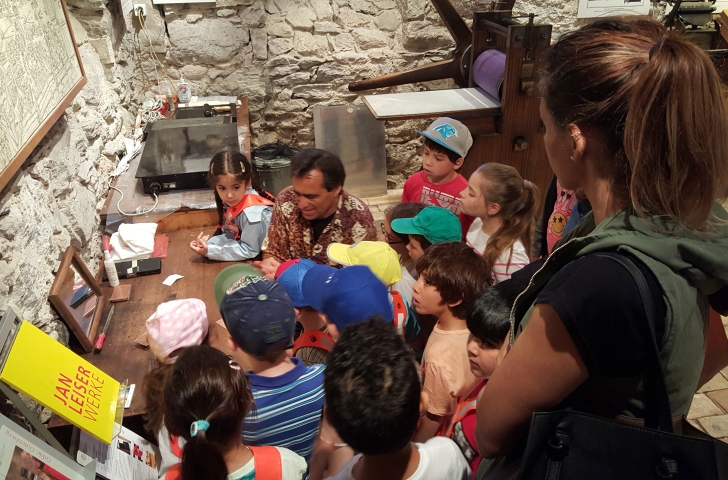 Eine Gruppe mit Kindern schaut sich den Kupferdruck im Ortsmuseum Maur an. 