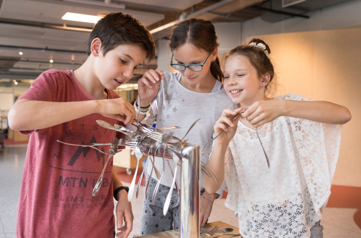 Drei Kinder versuchen sich an der Erfinderwerkstatt im Technorama Winterthur. 