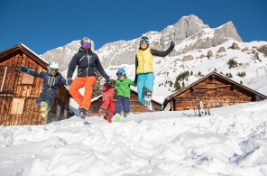 Familie springt nach dem Skifahren in Braunwald in den Schnee.