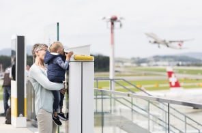 Mutter und Kind beobachten durch ein Fernrohr das Geschehen am Flughafen Zürich. 
