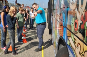 A chauffeur instructing a group of school children in front of the ZVV school bus.