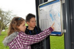 Two school children practising how to read the station plan