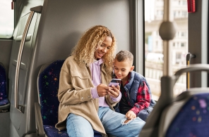 Eine Mutter ist mit ihrem Kind unterwegs im Bus und prüft ihren Anschluss in der ZVV-App.