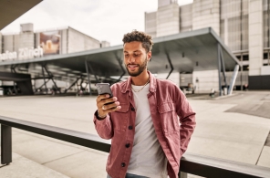 Ein junger Mann an der Haltestelle Zürich Flughafen prüft in der ZVV-App ob seine Verbindung pünktlich fährt.
