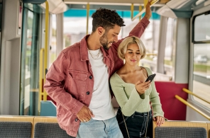 Ein junges Paar unterwegs im Tram, sie zeigt ihm wieviel Reisetage sie bereits gesammelt hat.